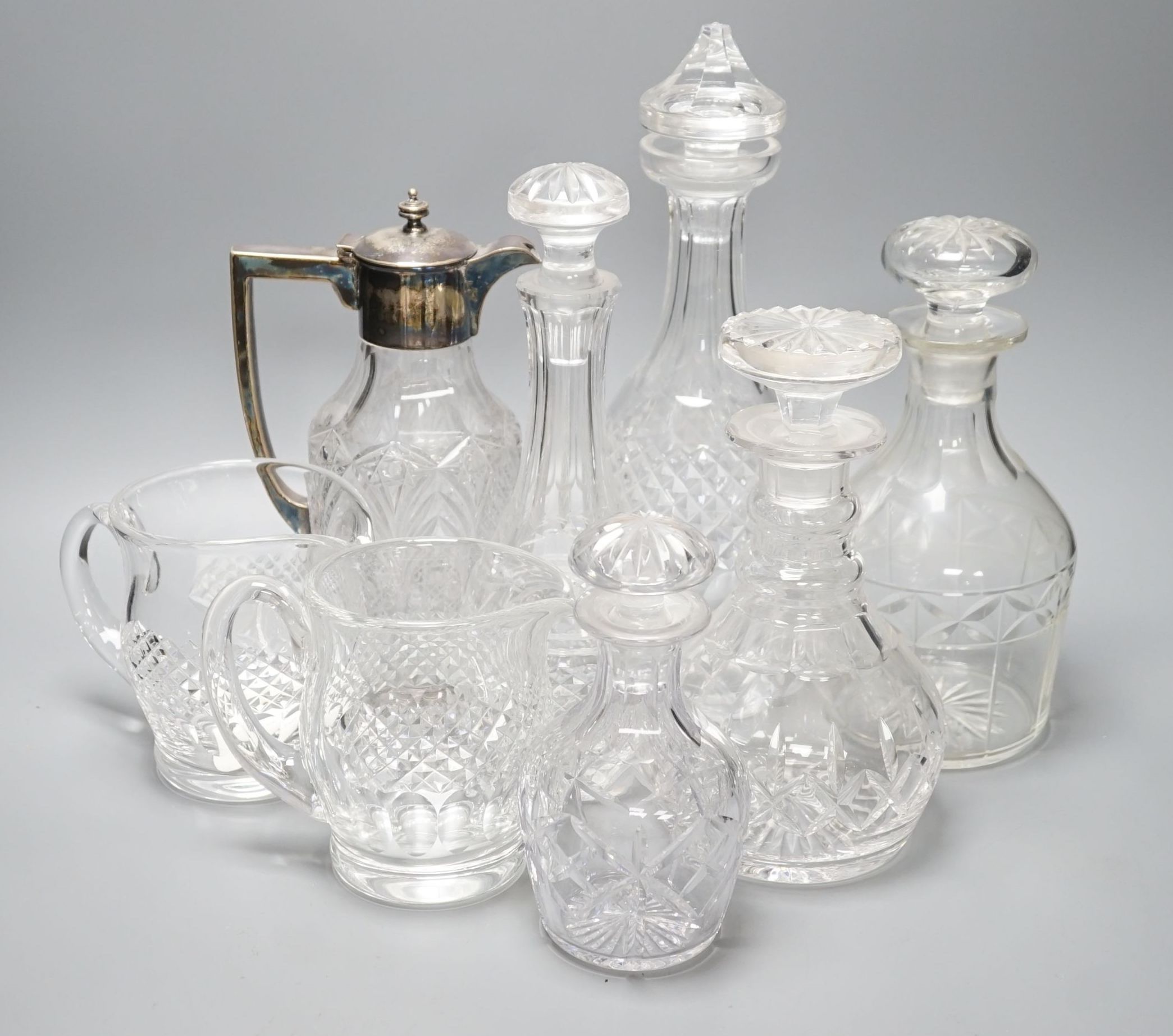 A group of assorted cut glass including decanters, a silver mounted claret jug, two milk jugs, tallest 33cm
